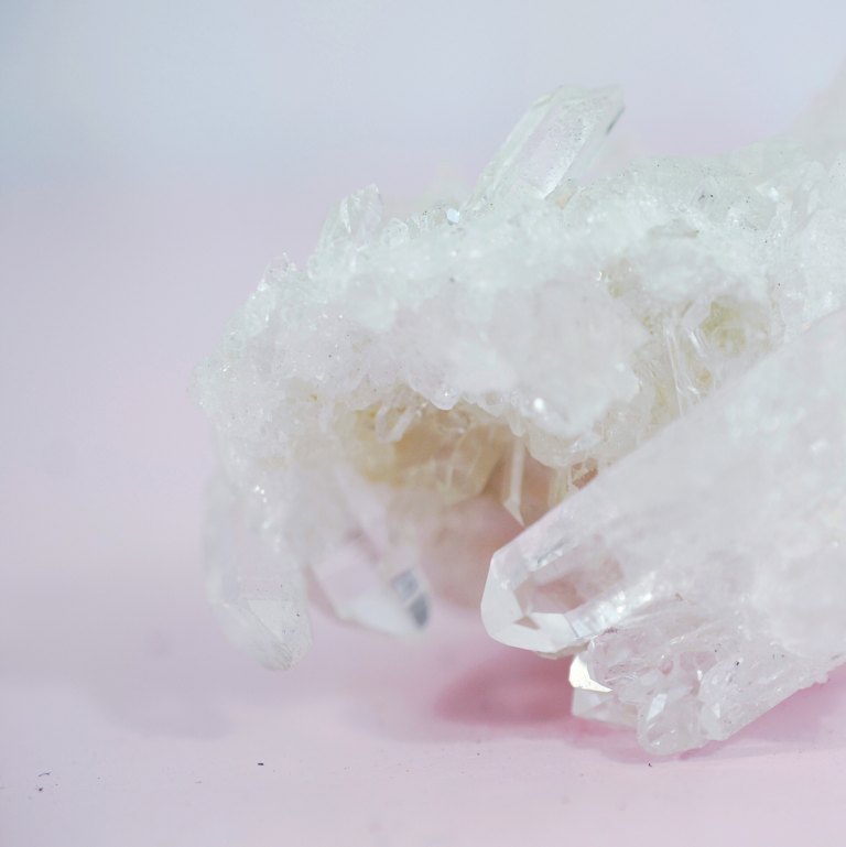 Close-up of clear quartz crystal clusters against a soft pink background, a neutral still-life standing in for later unrelated blog content